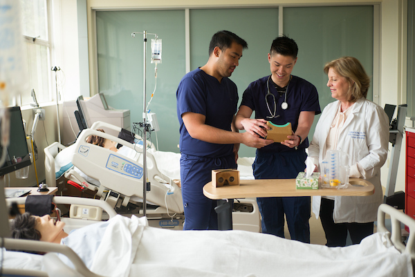 Two nursing students and a professor in a lab.
